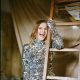 Gabrielle Aplin smiles in a silver sequin dress holding onto a wooden ladder