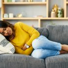 Shot of a young woman suffering from stomach cramps at home