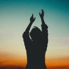 A person with upraised hands silhouetted against an evening sky, symbolising the benefits of meditation