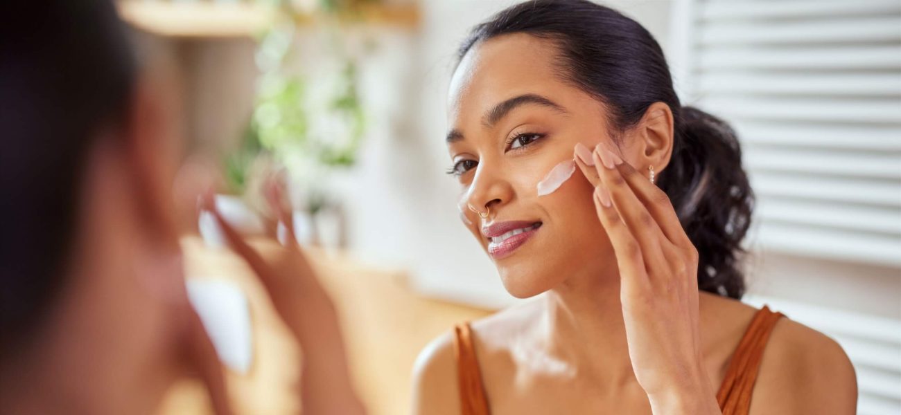 A woman applying moisturiser to her face