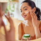 A woman applying moisturiser to her face