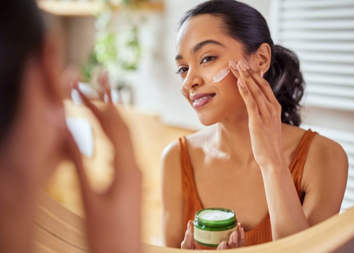 A woman applying moisturiser to her face