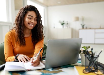 A female student making notes from a laptop