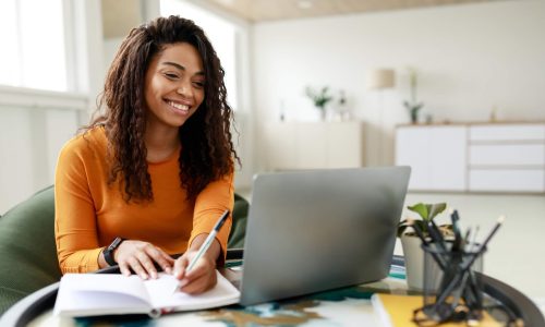 A female student making notes from a laptop