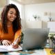 A female student making notes from a laptop