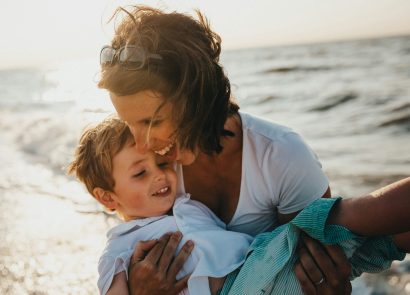 A happy mother carrying her son on the beach